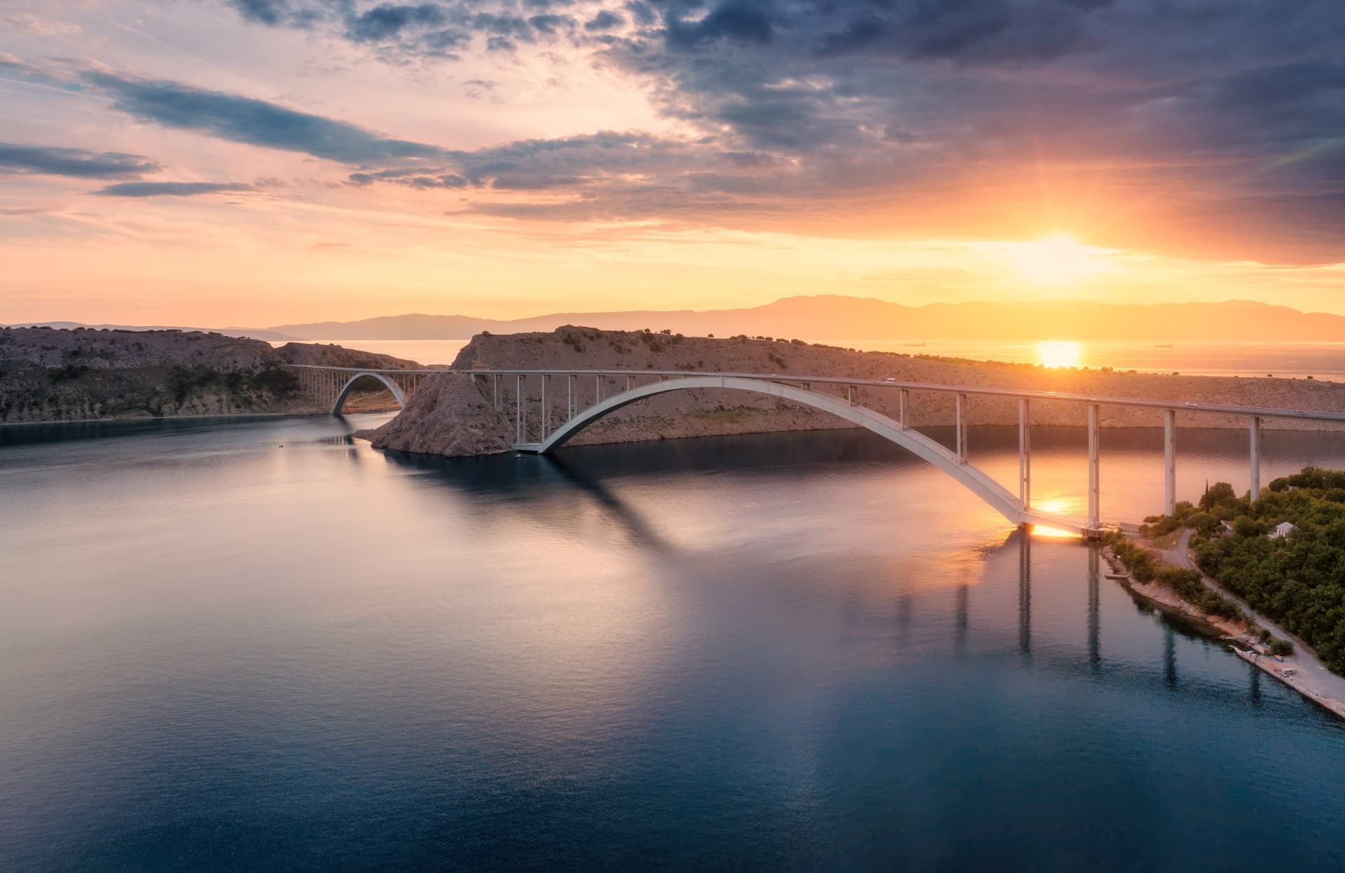Arched bridge spanning calm water at sunset