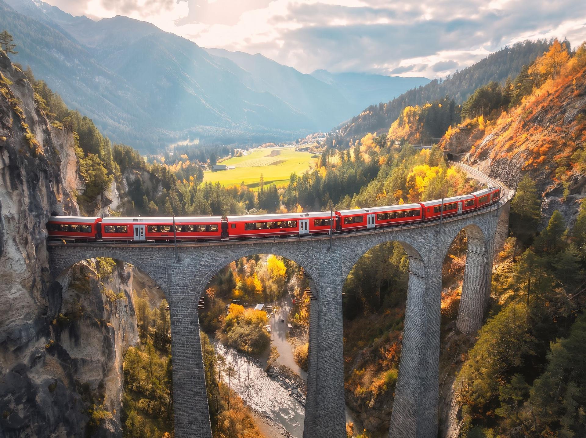 A red alpine train crossing a stone viaduct through an autumn valley
